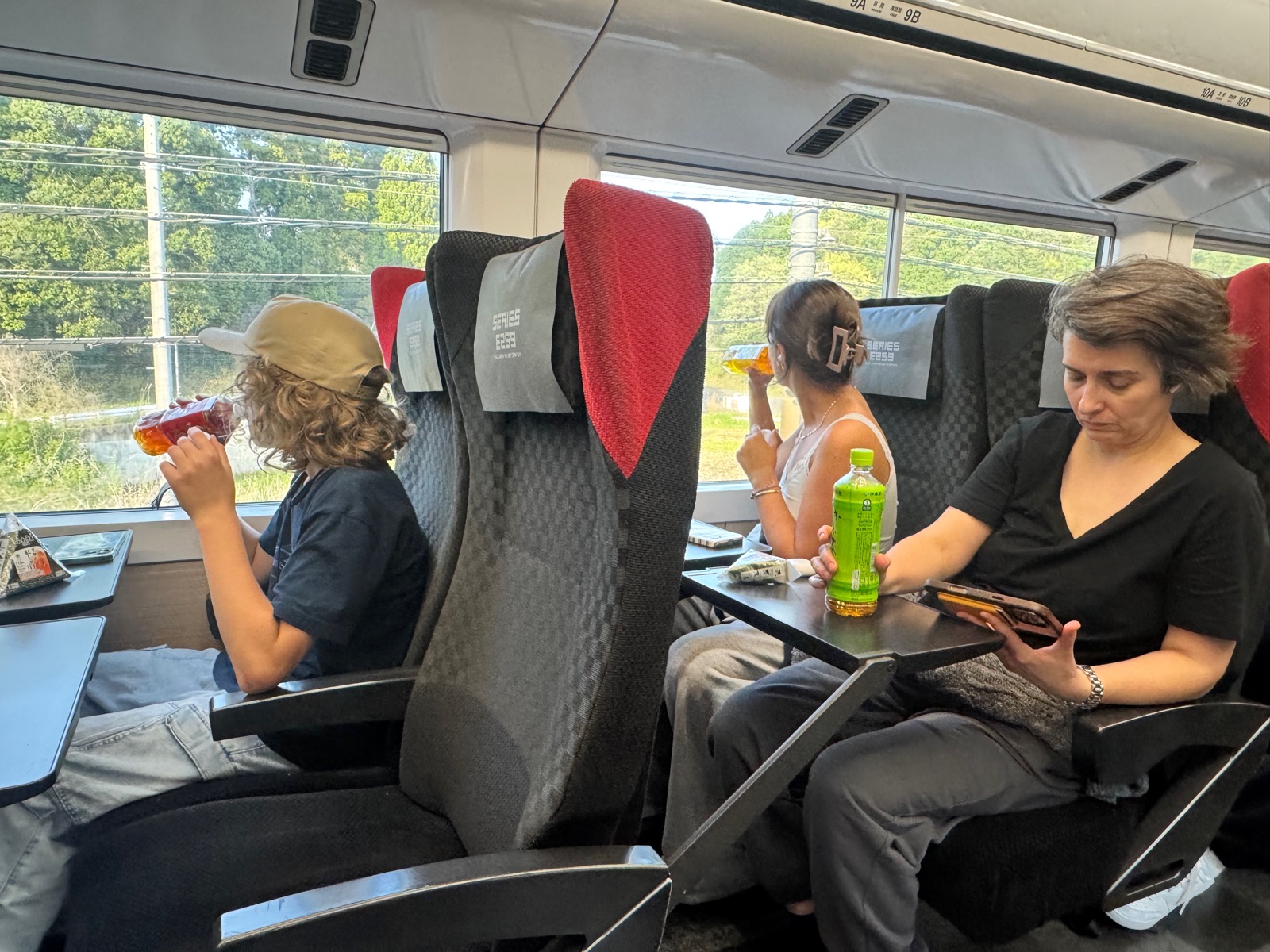 Family on the Narita Express, drinking Japanese drinks on the way to Shinjuku