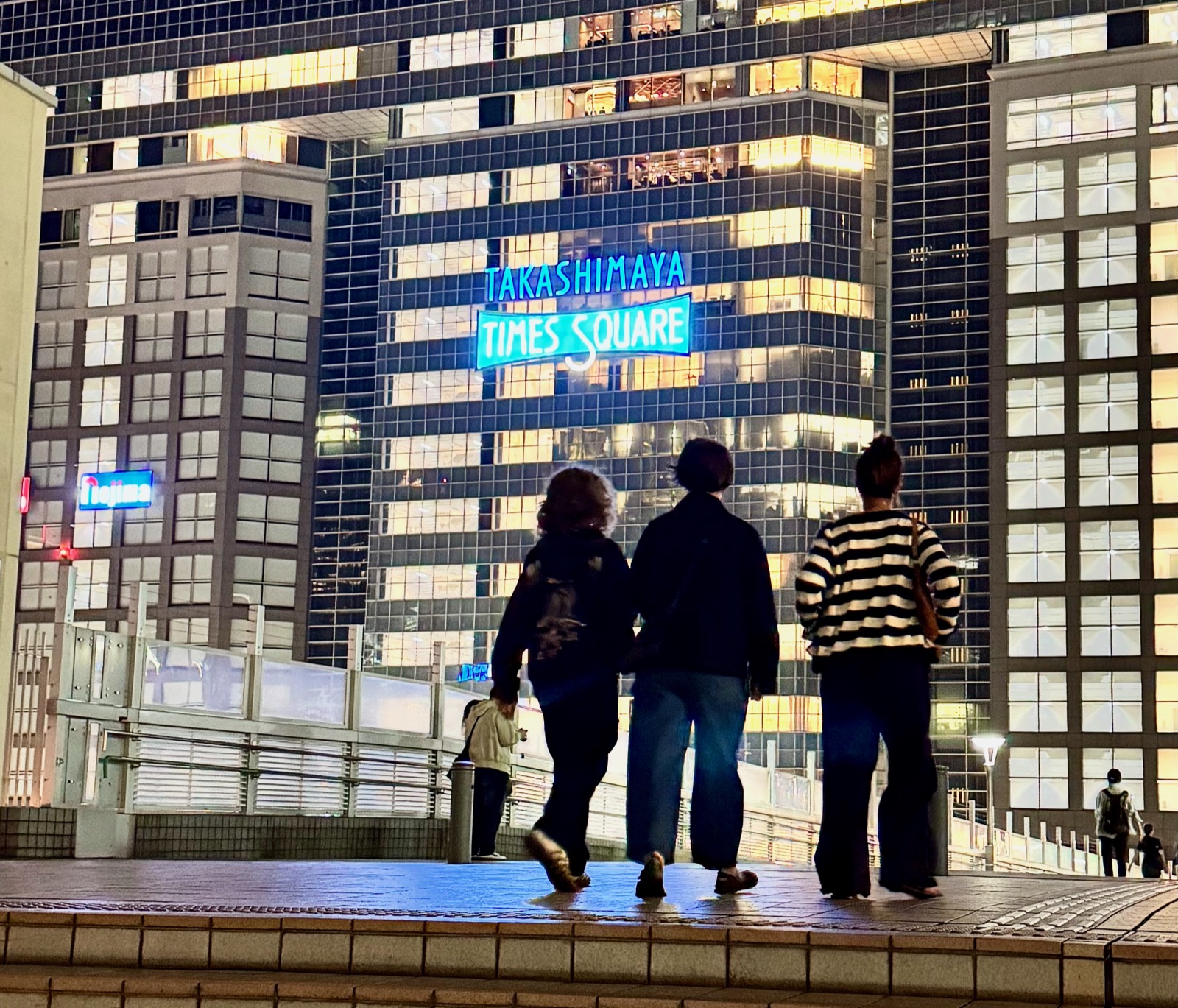 Family walking toward Takashimaya Times Square in Shinjuku at night