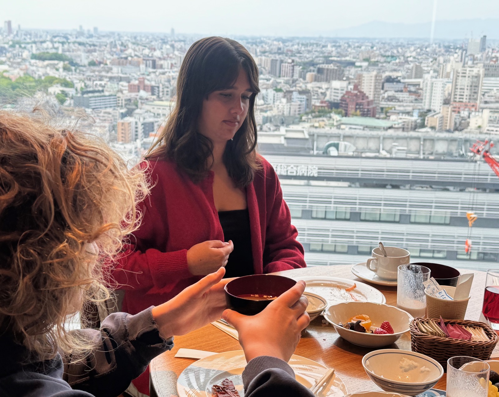 Seraphima at breakfast with panoramic Shinjuku view through the windows