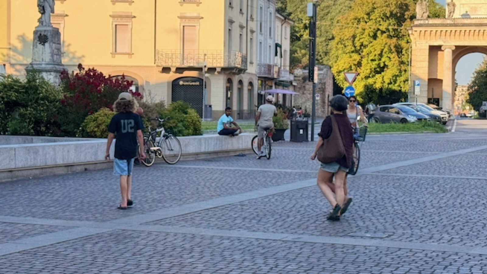 Crossing the cobbled piazza by Porta Serio at golden hour, bikes everywhere
