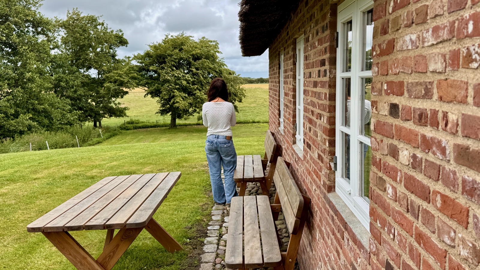 Natalia at the thatched brick holiday house, fields behind