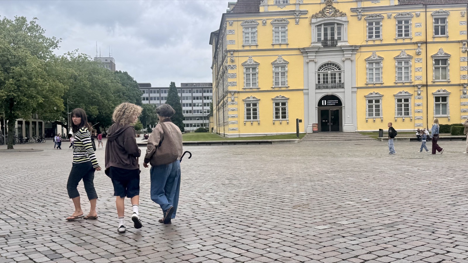 Crossing the cobbled Schlossplatz in front of the yellow Oldenburger Schloss