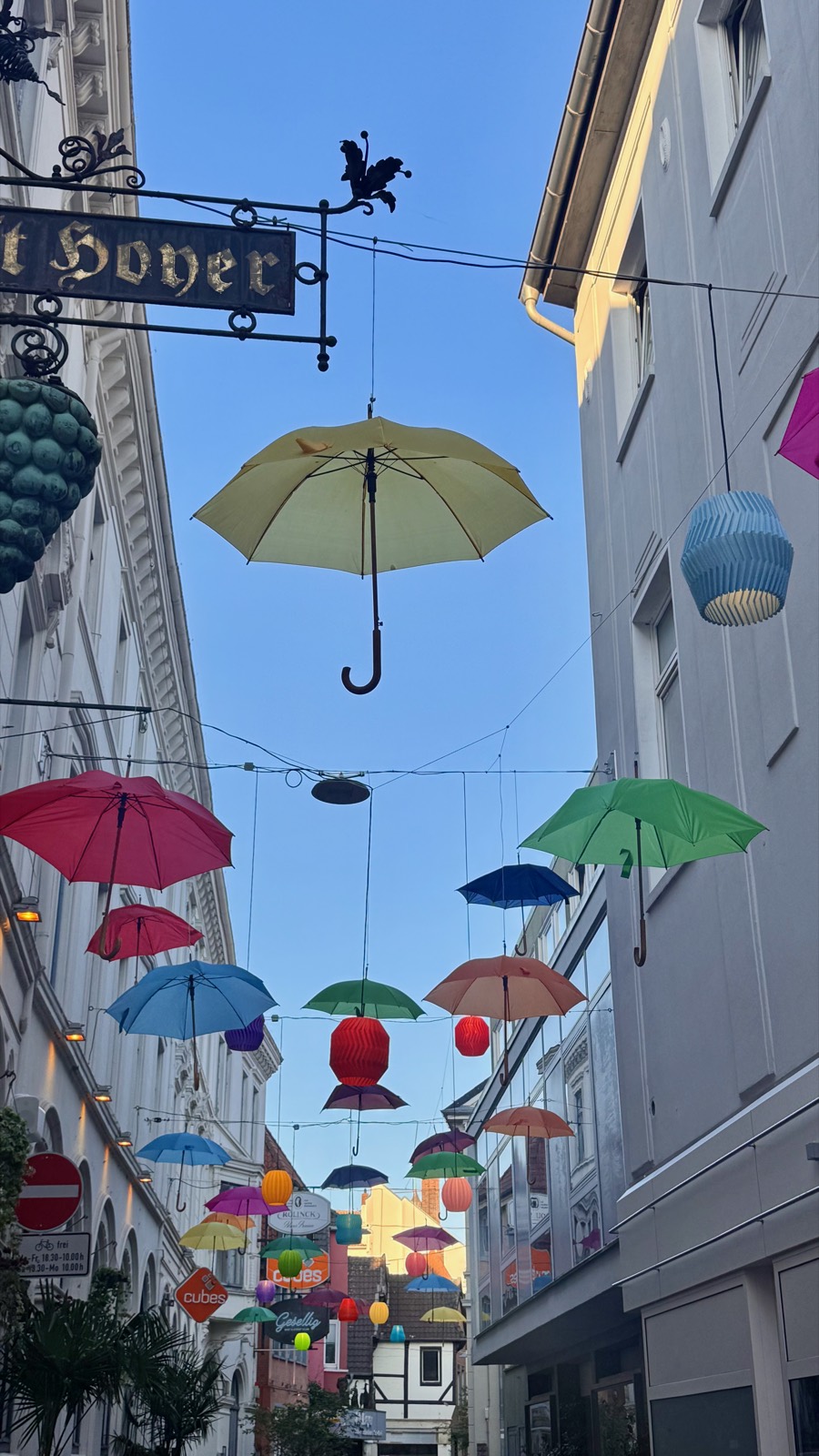 Umbrellas and lanterns strung over an Oldenburg lane at dusk