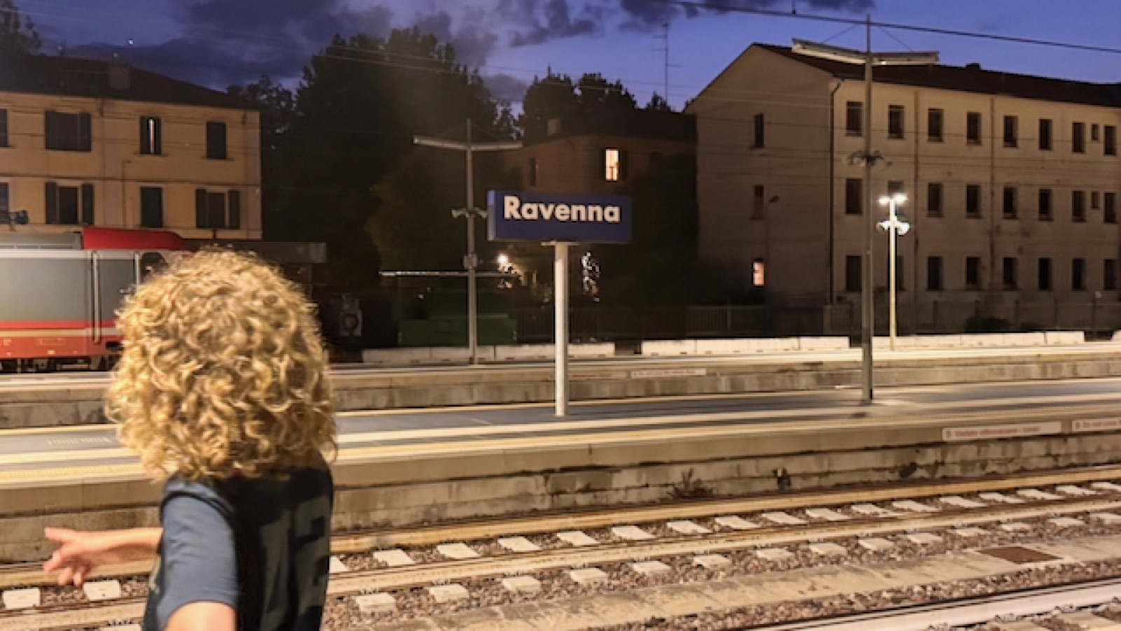 Luca on the platform under the Ravenna station sign at dusk