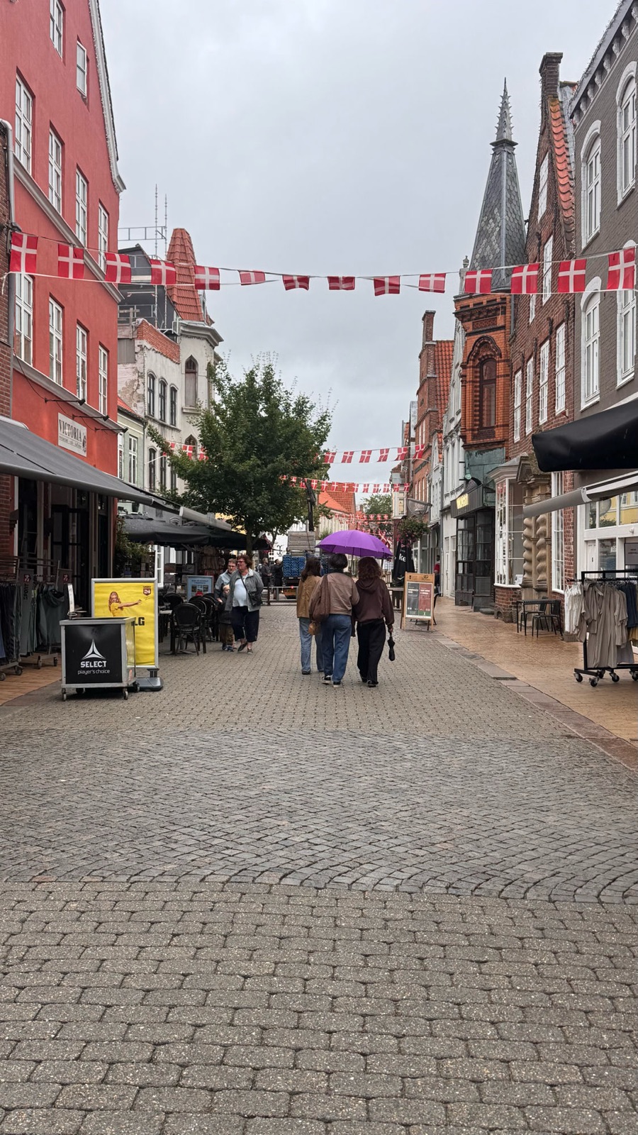 Storegade under Dannebrog bunting, purple umbrella leading the way